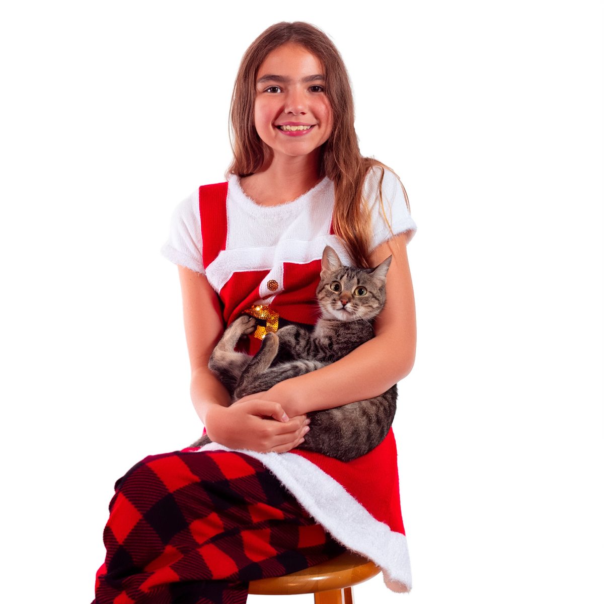 Smiling girl in a red and white holiday outfit holding a tabby cat